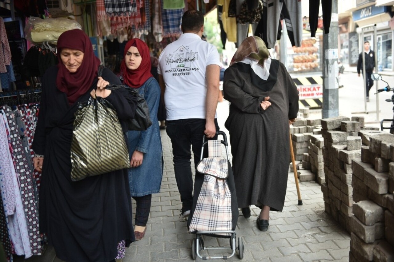 Belediye ekipleri, yaşlıların torbalarını taşıyor