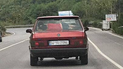 Otomobilin arka camıyla koltuğu arasında uyuyan çocuğun tehlikeli yolculuğu kamerada